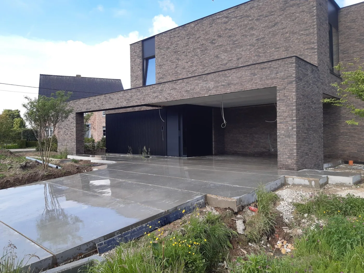 Gestorte betonvloer rond een woning tijdens de buitenaanleg