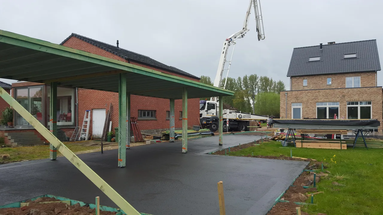 Antraciet betonnen terras dat doorloopt onder de carport in Stevoort