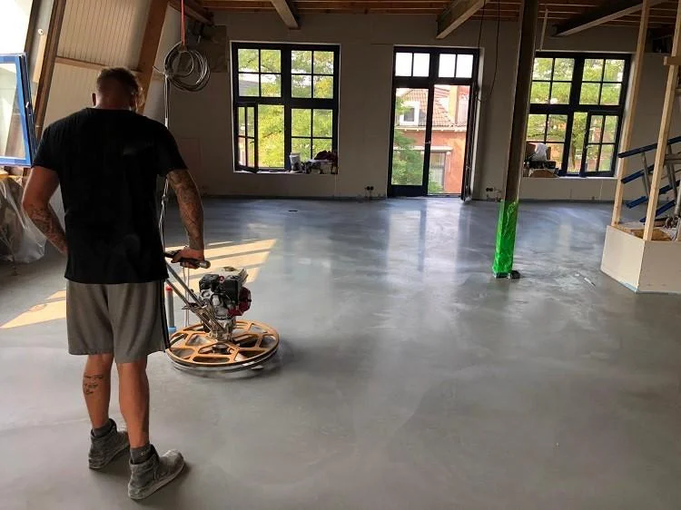 Medewerker poliert een betonvloer binnenshuis met een kleinere vlindermachine